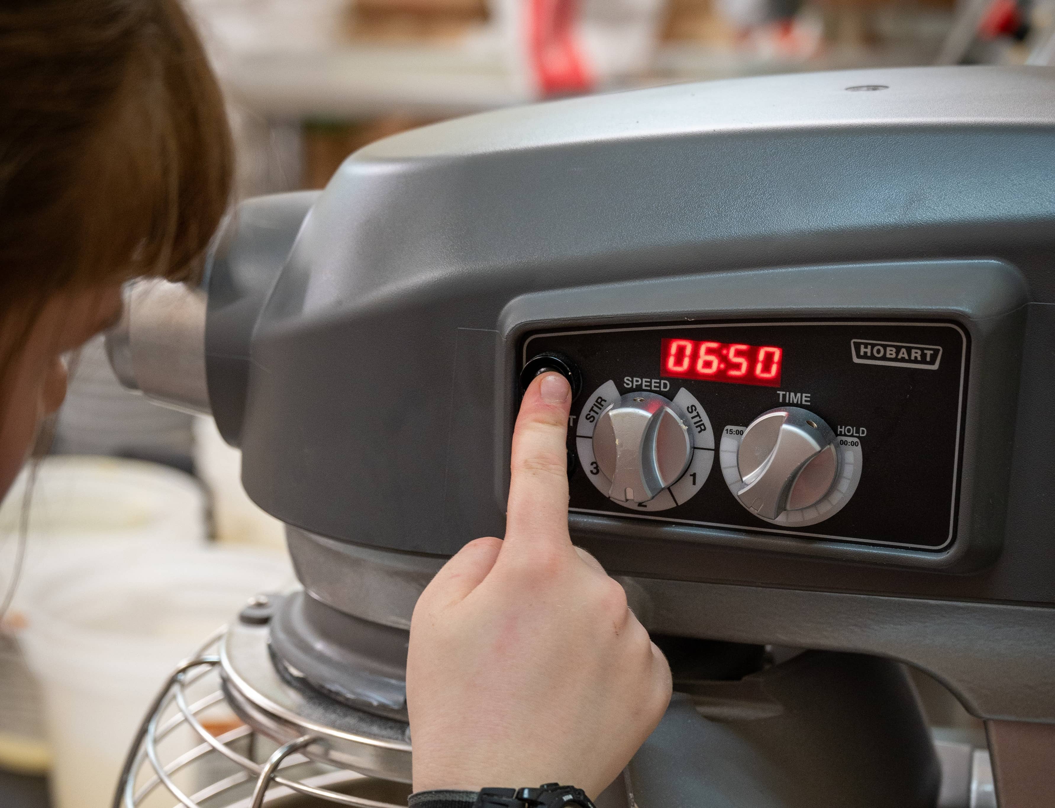 Baker pushing a button on a Hobart Legacy Plus mixer